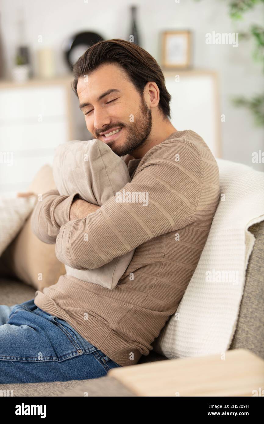 handsome cheerful young man sitting on the couch at home Stock Photo