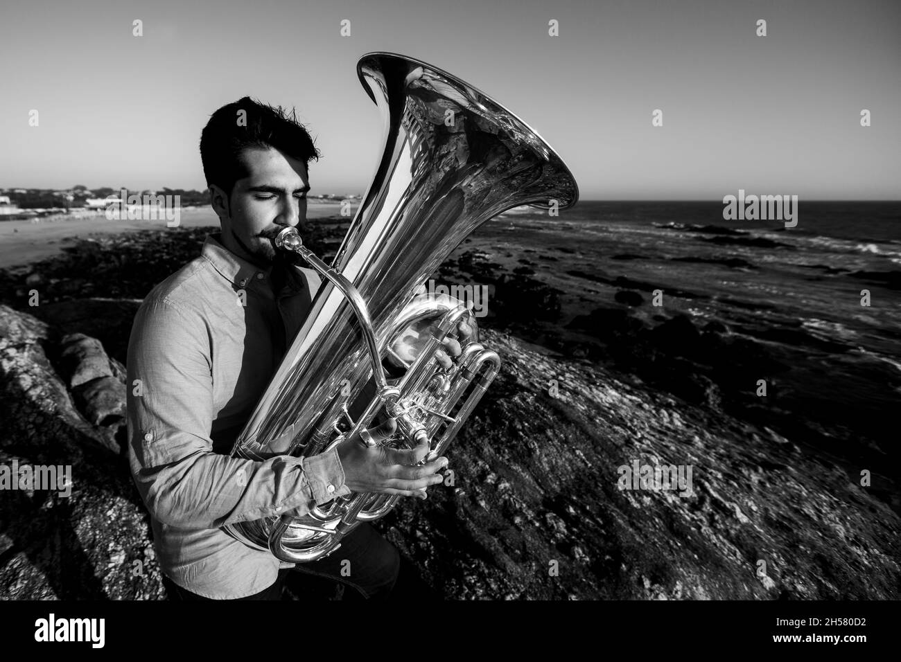 A musician with a tuba on the Ocean beach. Black and white photo. Stock Photo