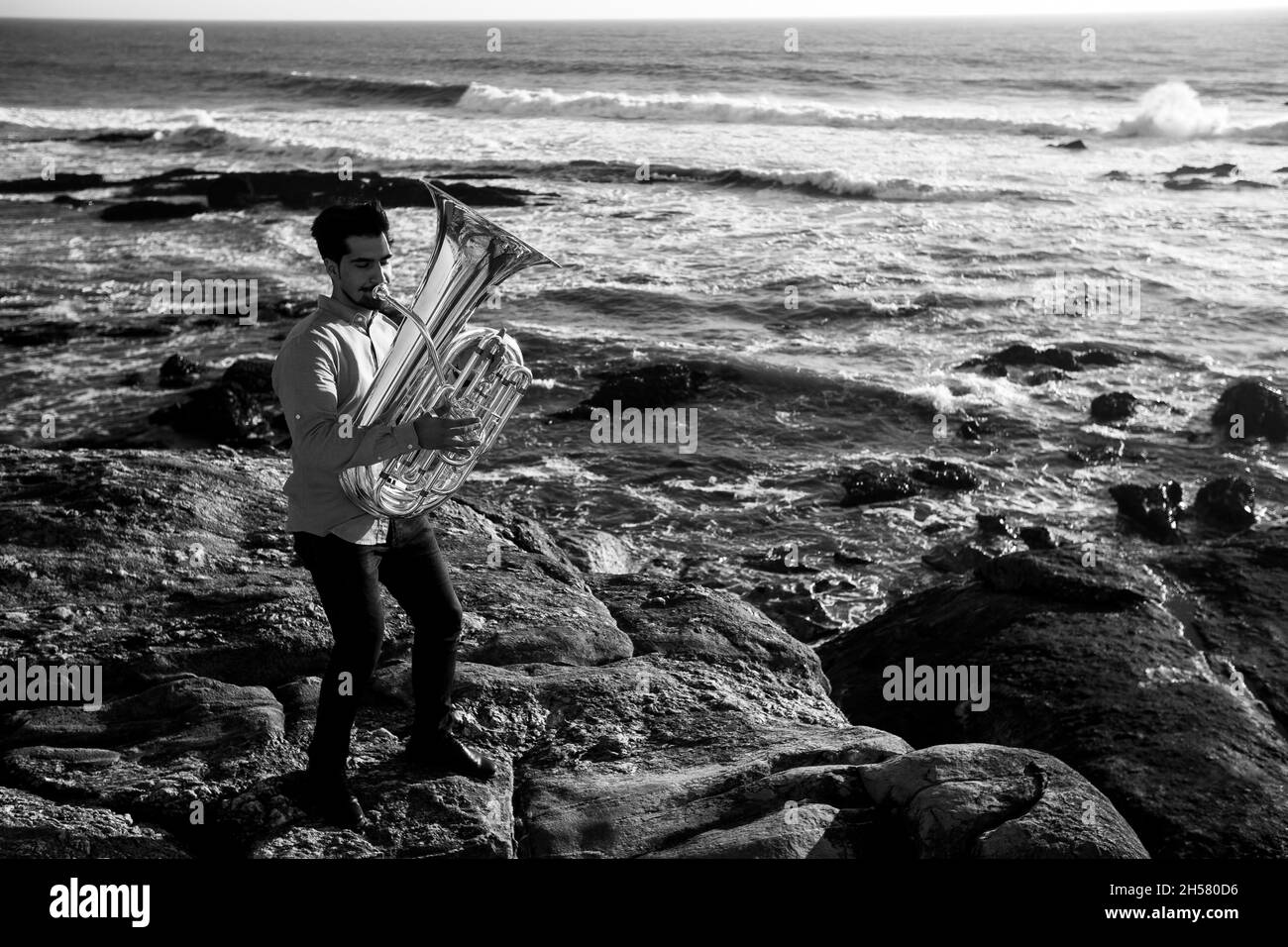 A musician man with a tuba on the Ocean beach. Black and white photo. Stock Photo