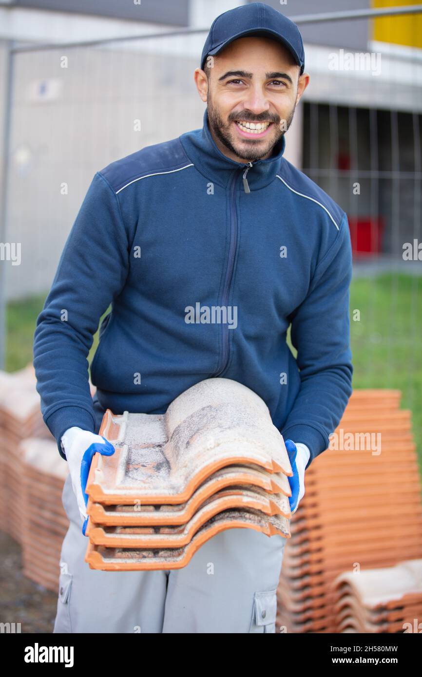 roofer builder holding tiles at construction site Stock Photo