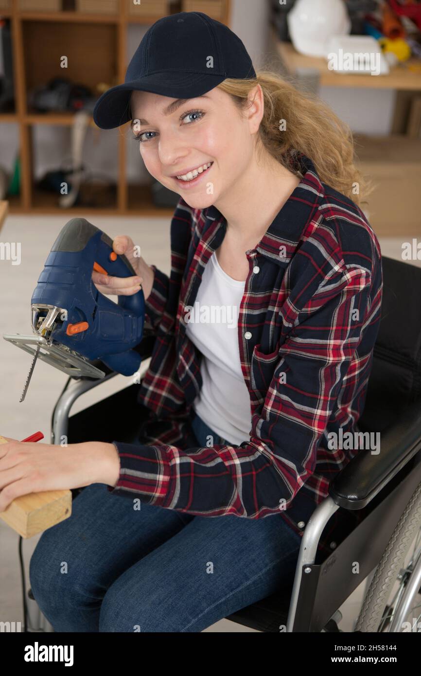 disabled girl using electric jigsaw Stock Photo