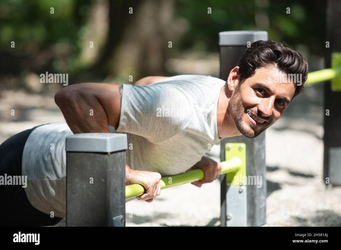 man doing triceps dips on bars at park exercising outdoors Stock Photo
