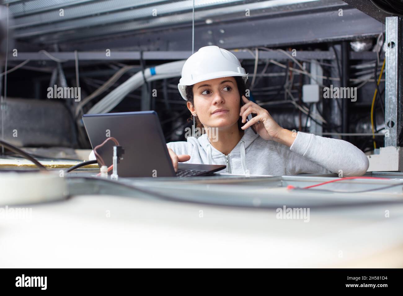 female contractor using laptop in roofspace Stock Photo