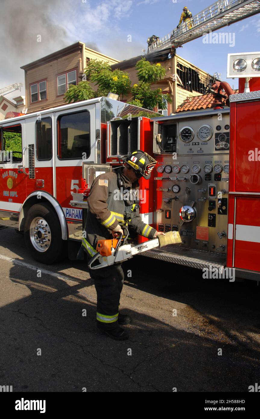San Diego City Firefighter prepares chainsaw during a structure fire in
