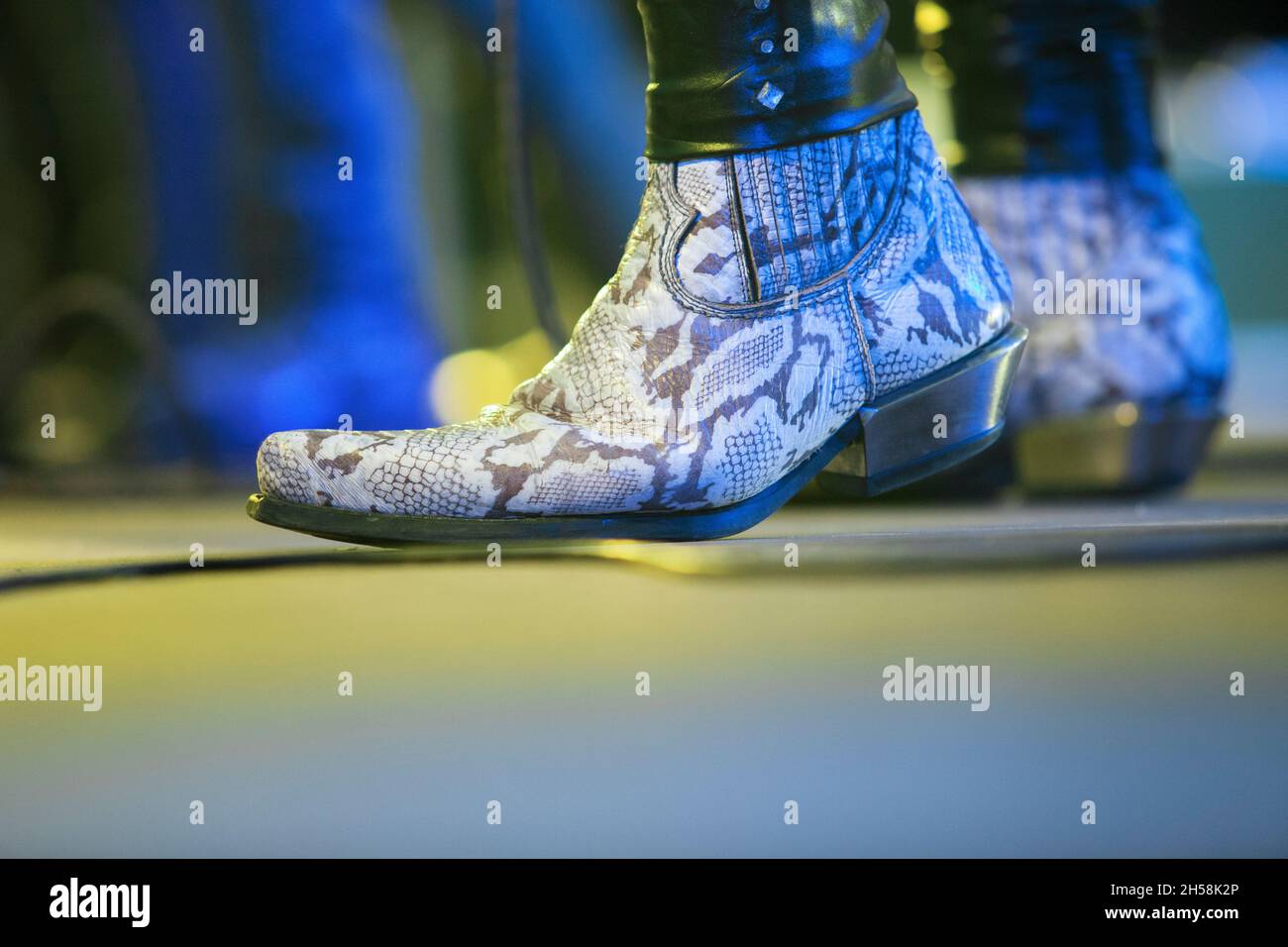 Snakeskin boots on stage. Hard rock musicians performing. Stock Photo