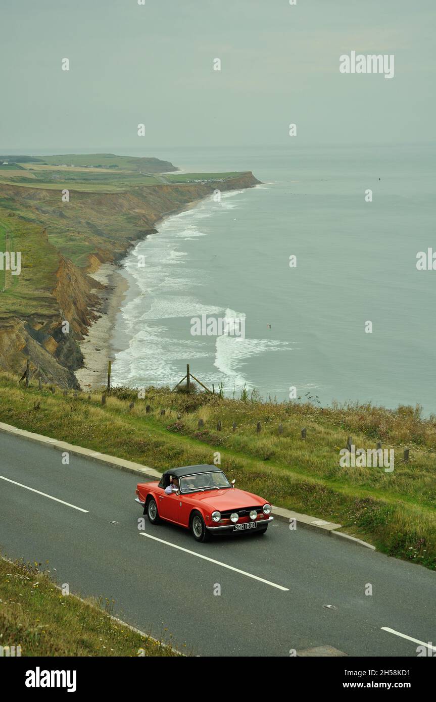 A Triumph TR5 on a classic car road rally on acoastal road on the Isle