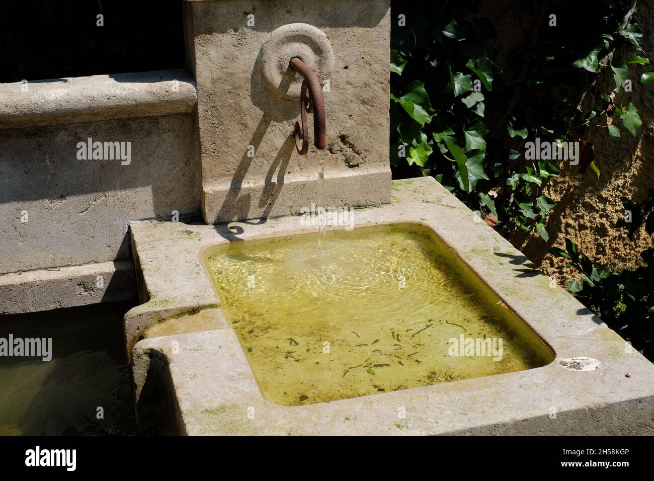 Small fountain with water flowing, in the garden of a house in Northern Italy Stock Photo