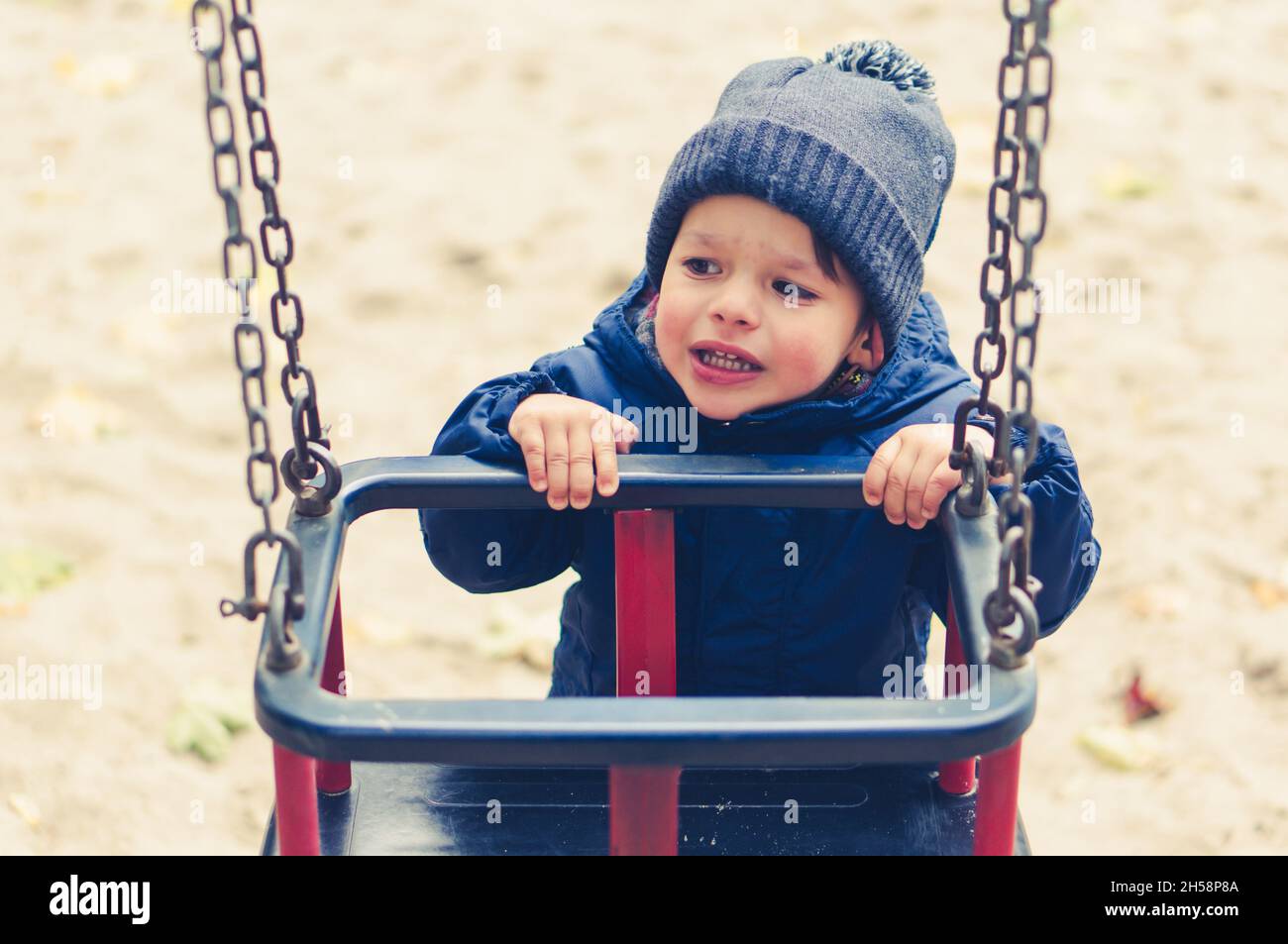 A cute little caucasian boy by a swing in a playground Stock Photo - Alamy