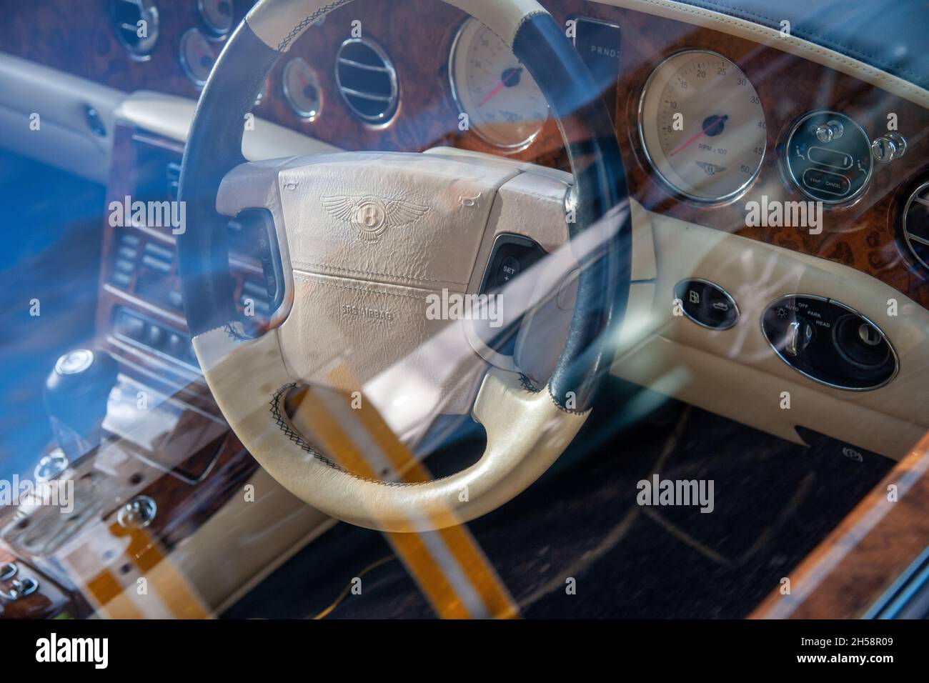 Steering wheel and dashboard of a Bentley GT Speed Coupe W12 viewed through reflections in the car's window Stock Photo