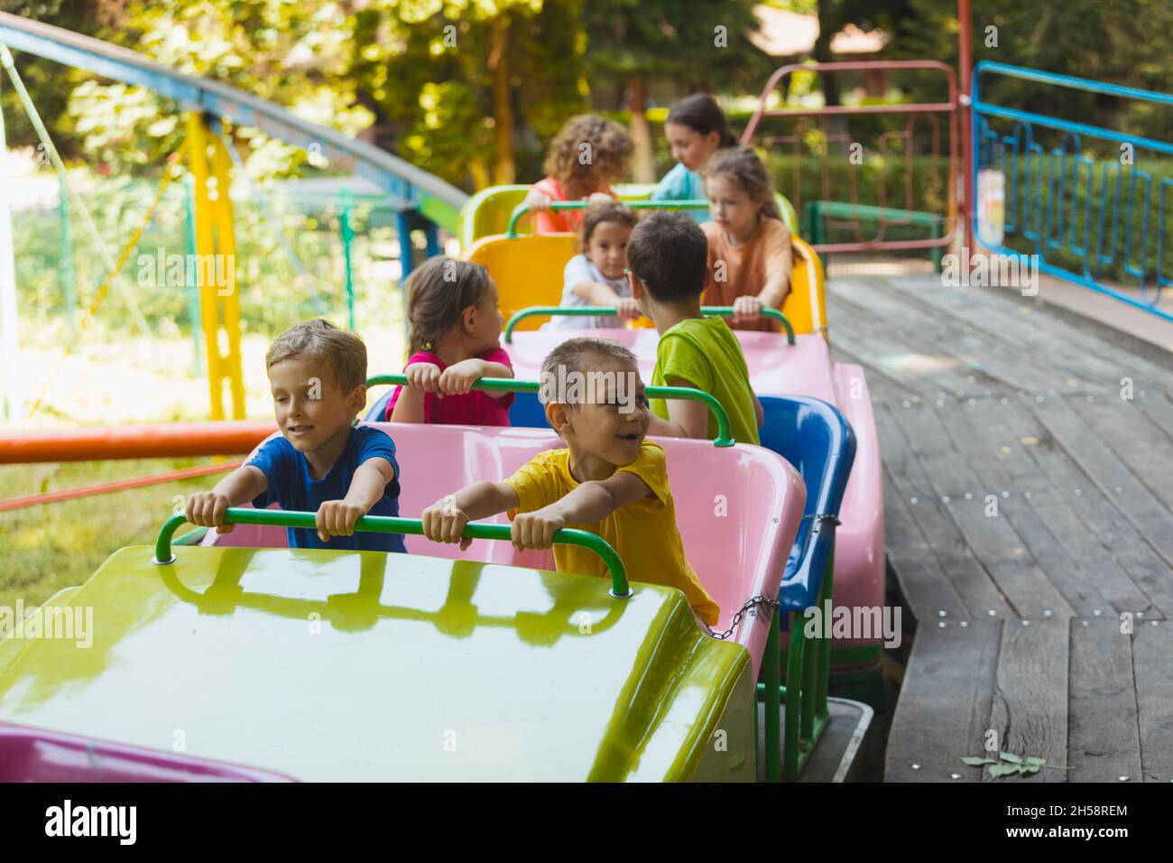 The happy kids on a roller coaster in the amusement park Stock Photo ...