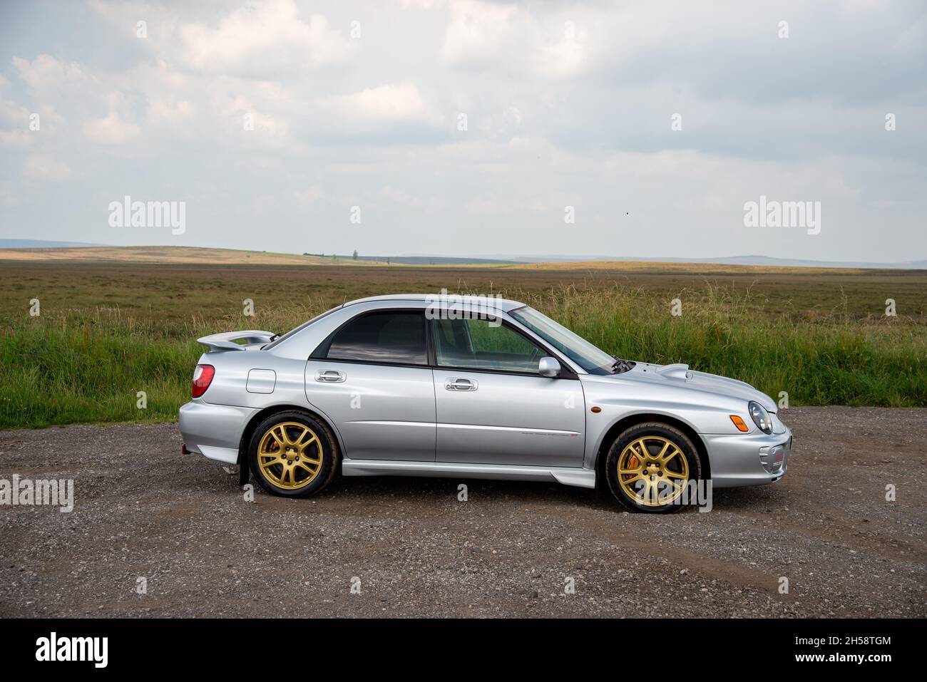 Silver Subaru Wrx Xti With Gold Wheels Parked On Gravel Beside Moorland In The Peak