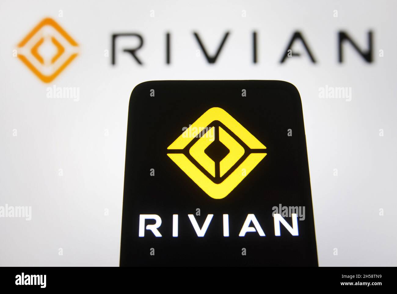 In this photo illustration, a Rivian Automotive LLC logo of an electric vehicle automaker logo is seen on a smartphone and a pc screen. Stock Photo
