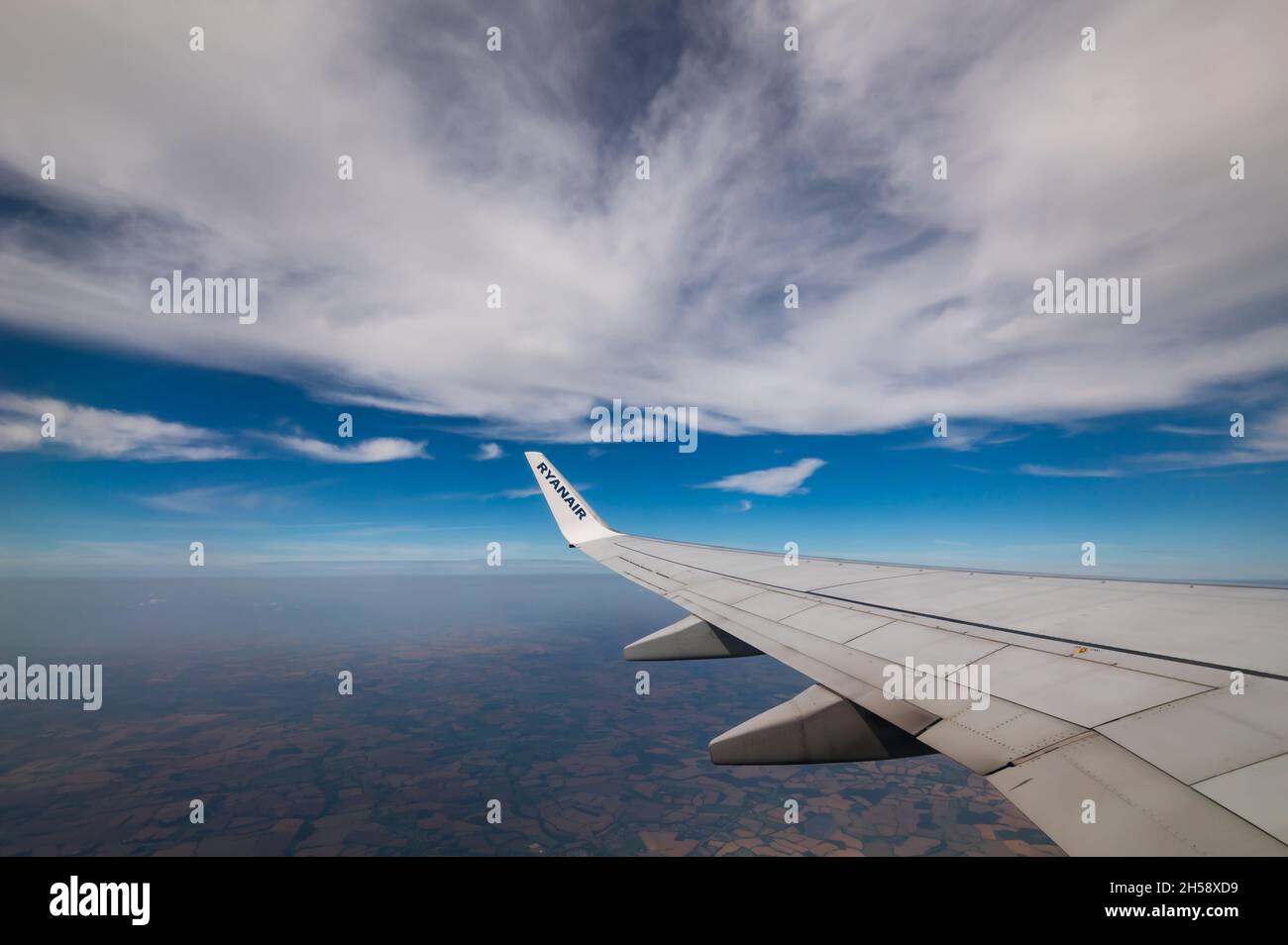 06/09/2021. Commercial Ryanair airborne airplane at high altitude. Cabin window view at wing with trademark name. Stock Photo