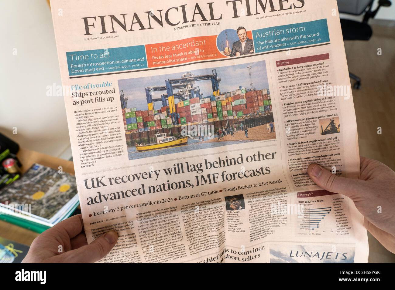 A man's hands holding a copy of the Financial Times newspaper with the headline that the UK recovery will lag behind other developed nations. 2021, UK Stock Photo