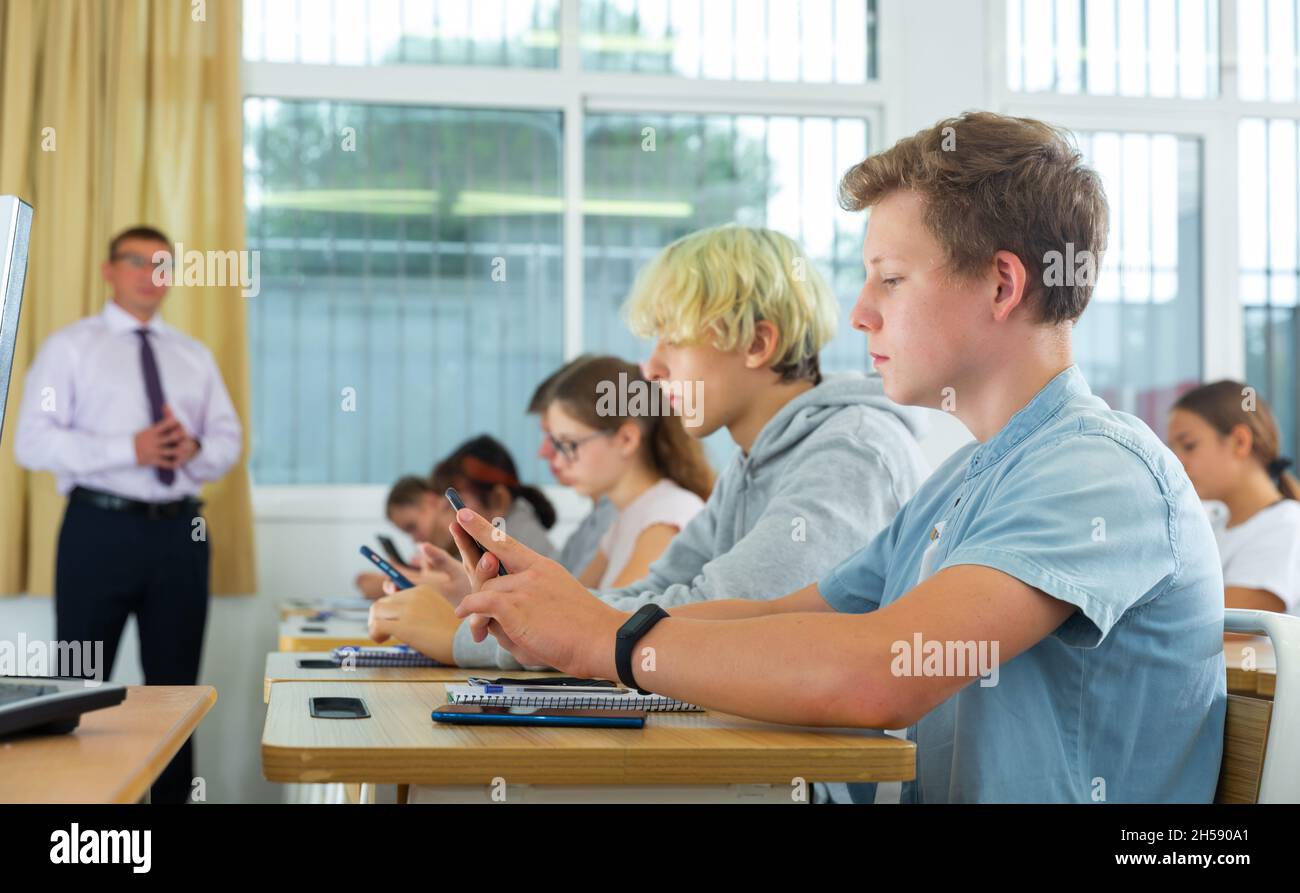 Teenage students using smartphones during lesson Stock Photo Alamy