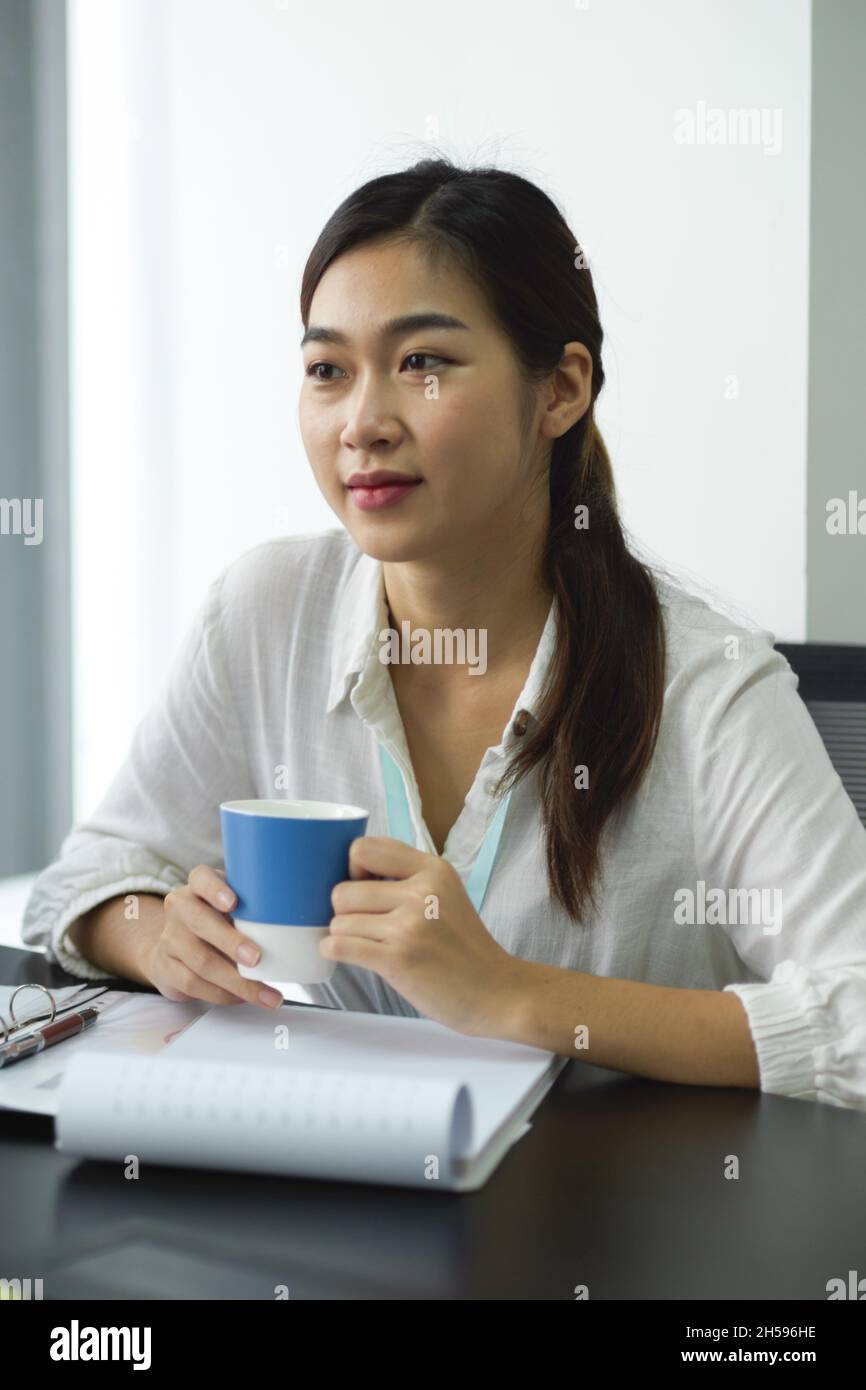Beautiful female business employee holding a coffee cup while sitting