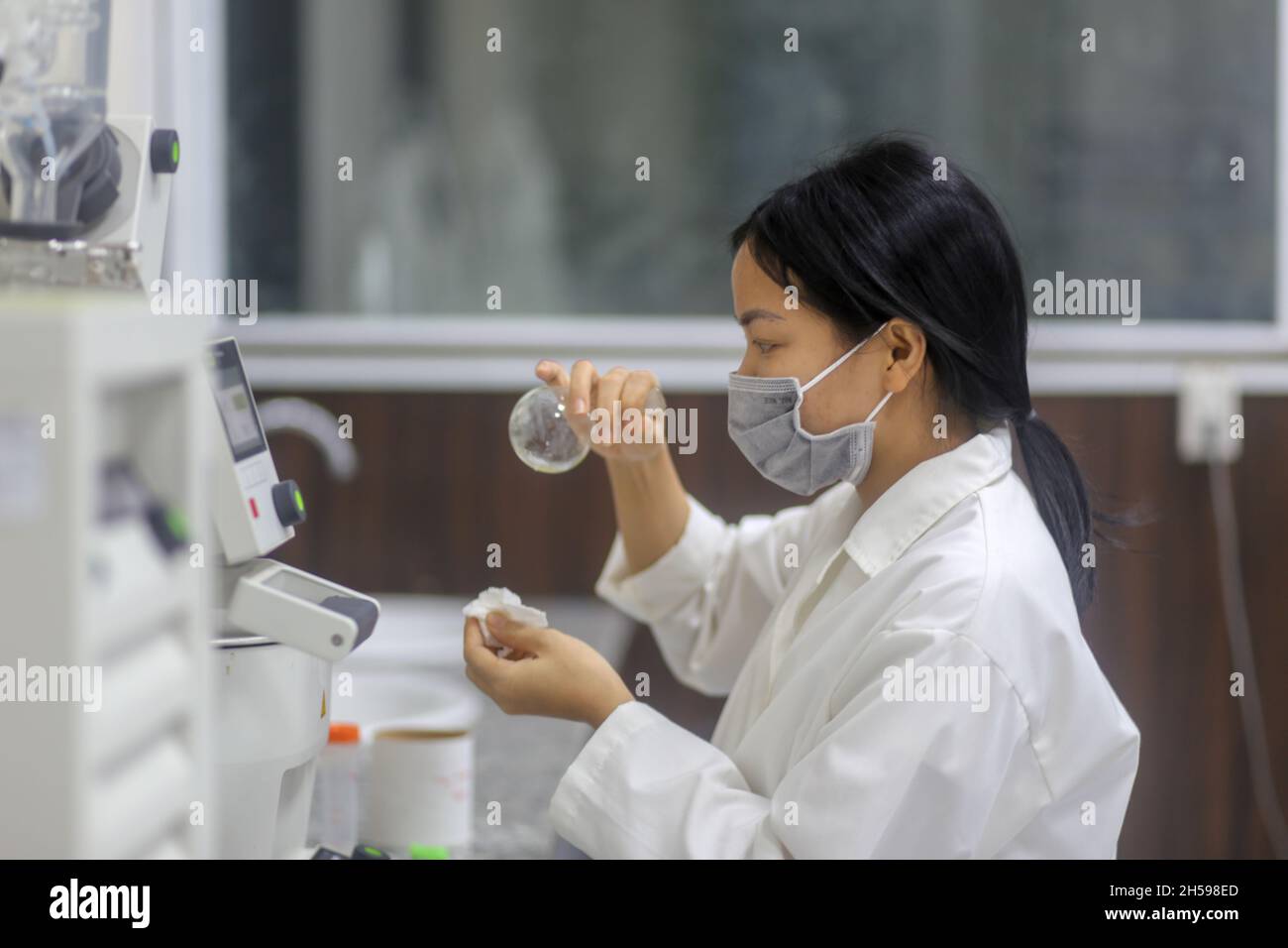 Asian woman scientist checking laboratory glass flask to make an experiment in the laboratory Stock Photo