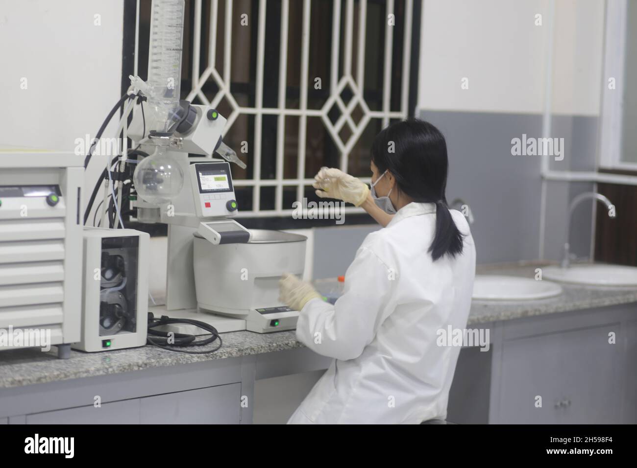 Asian woman scientist operating a rotary evaporator to make an experiment in the laboratory Stock Photo