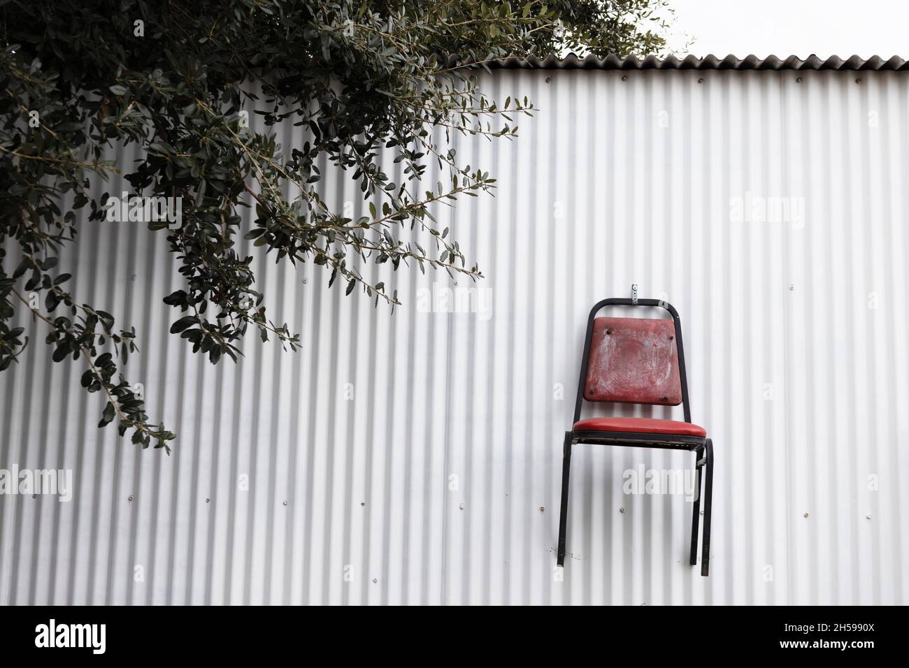 A chair fastened to the side of a building, too high to sit on Stock ...