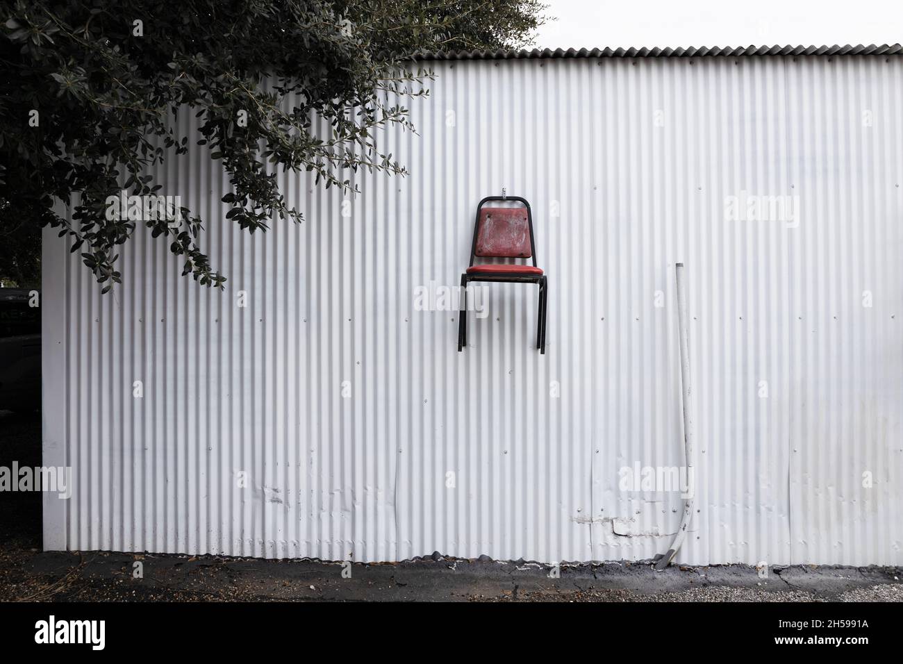 A chair fastened to the side of a building, too high to sit on Stock ...