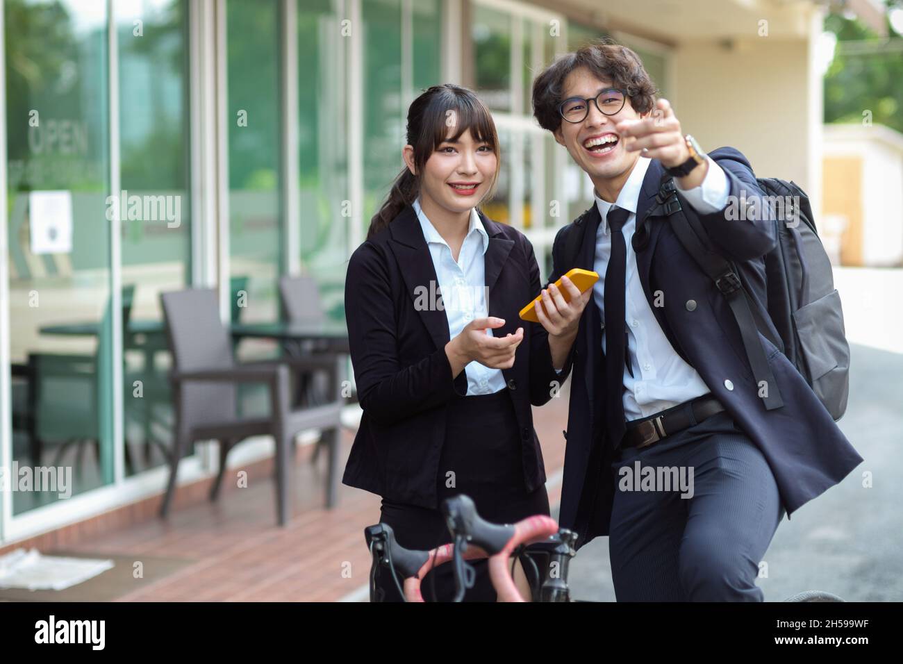 Asian businessman giving a directions advice to young female at the city street. Stock Photo