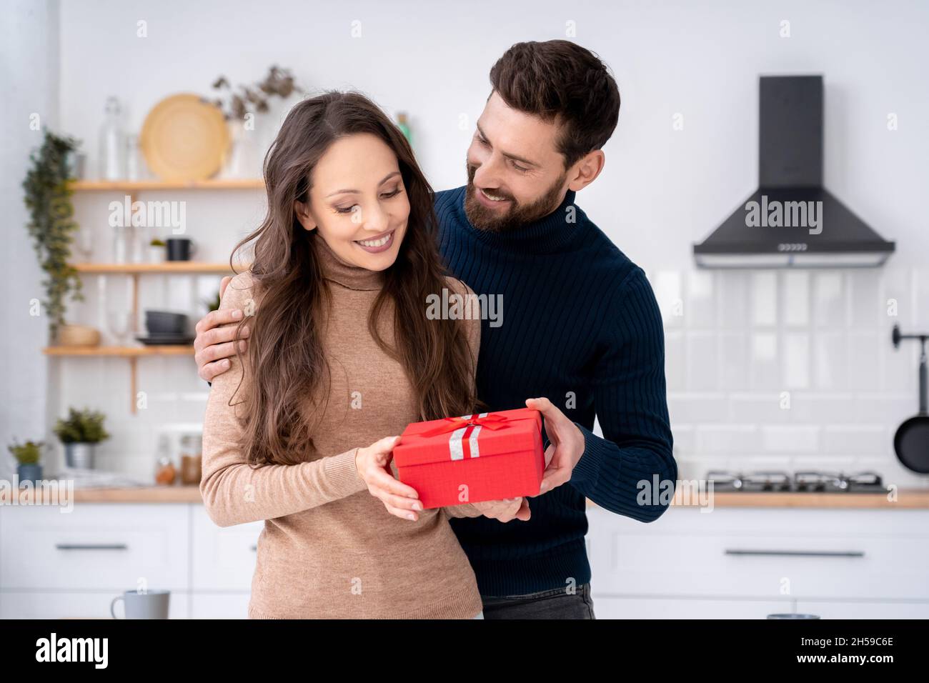 Loving husband surprising charming wife with present gift box on romantic day Stock Photo