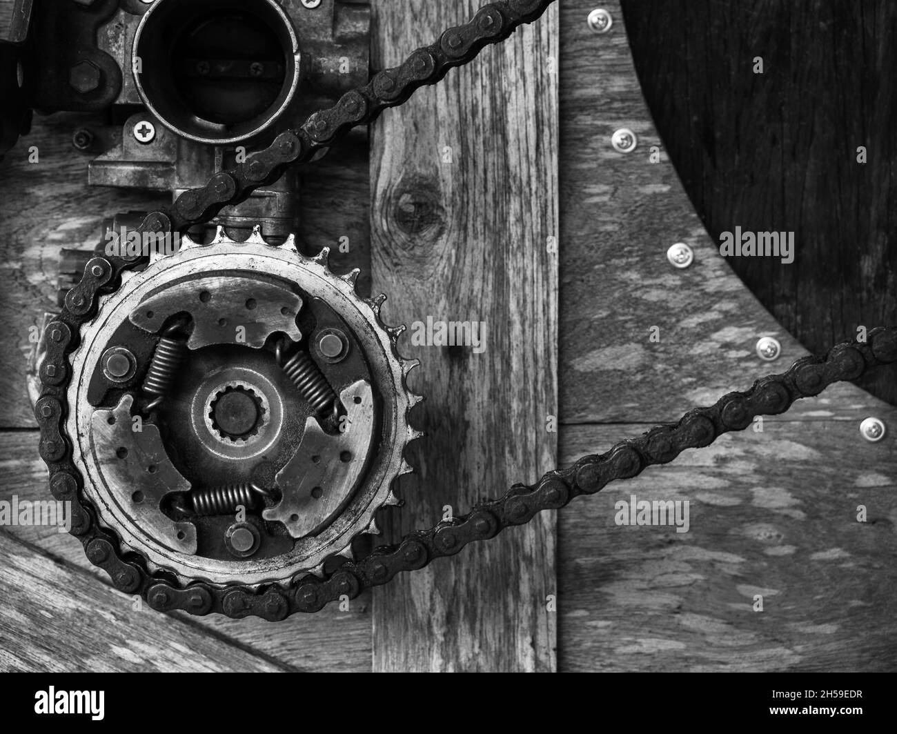 Old rusty gears mechanism arranged on wood background, black and white