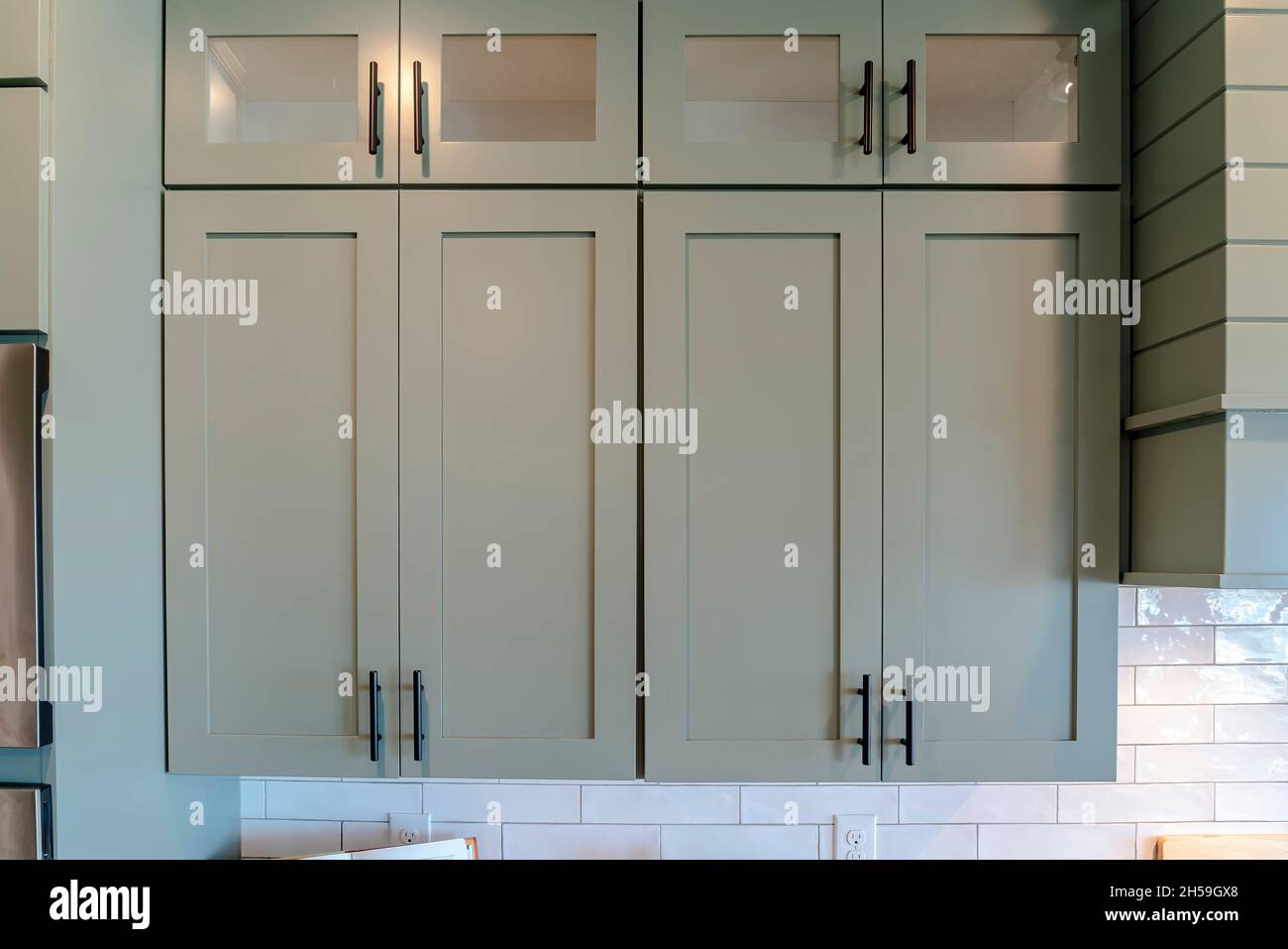 Wooden kitchen hanging with glass panes against white tile