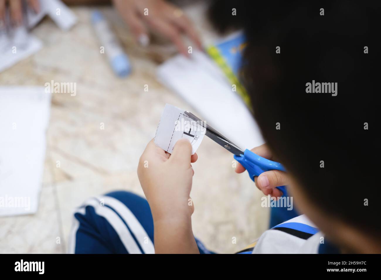 Childhood are learning to use scissors to cut paper Stock Photo - Alamy
