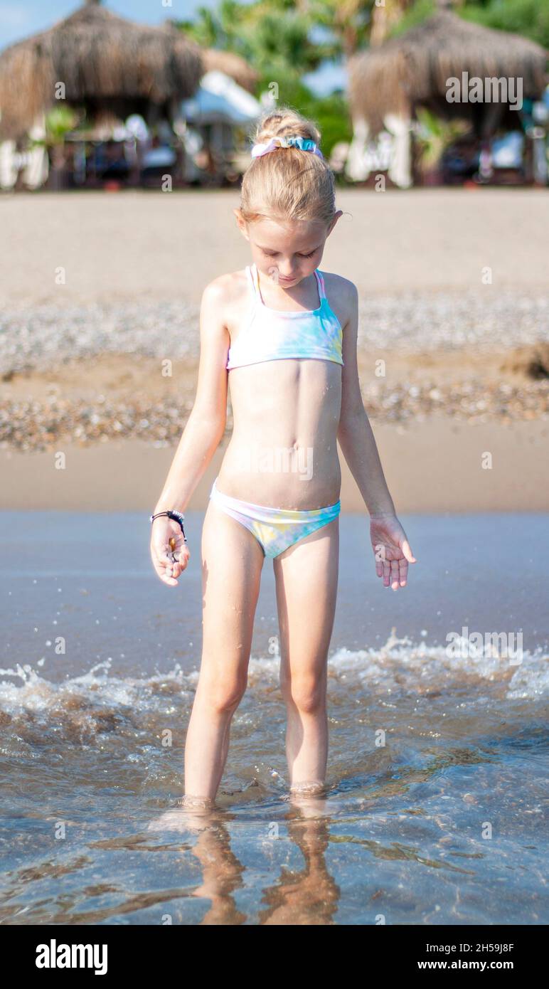 Little girl in a bathing suit playing on the beach by the sea Stock Photo -  Alamy
