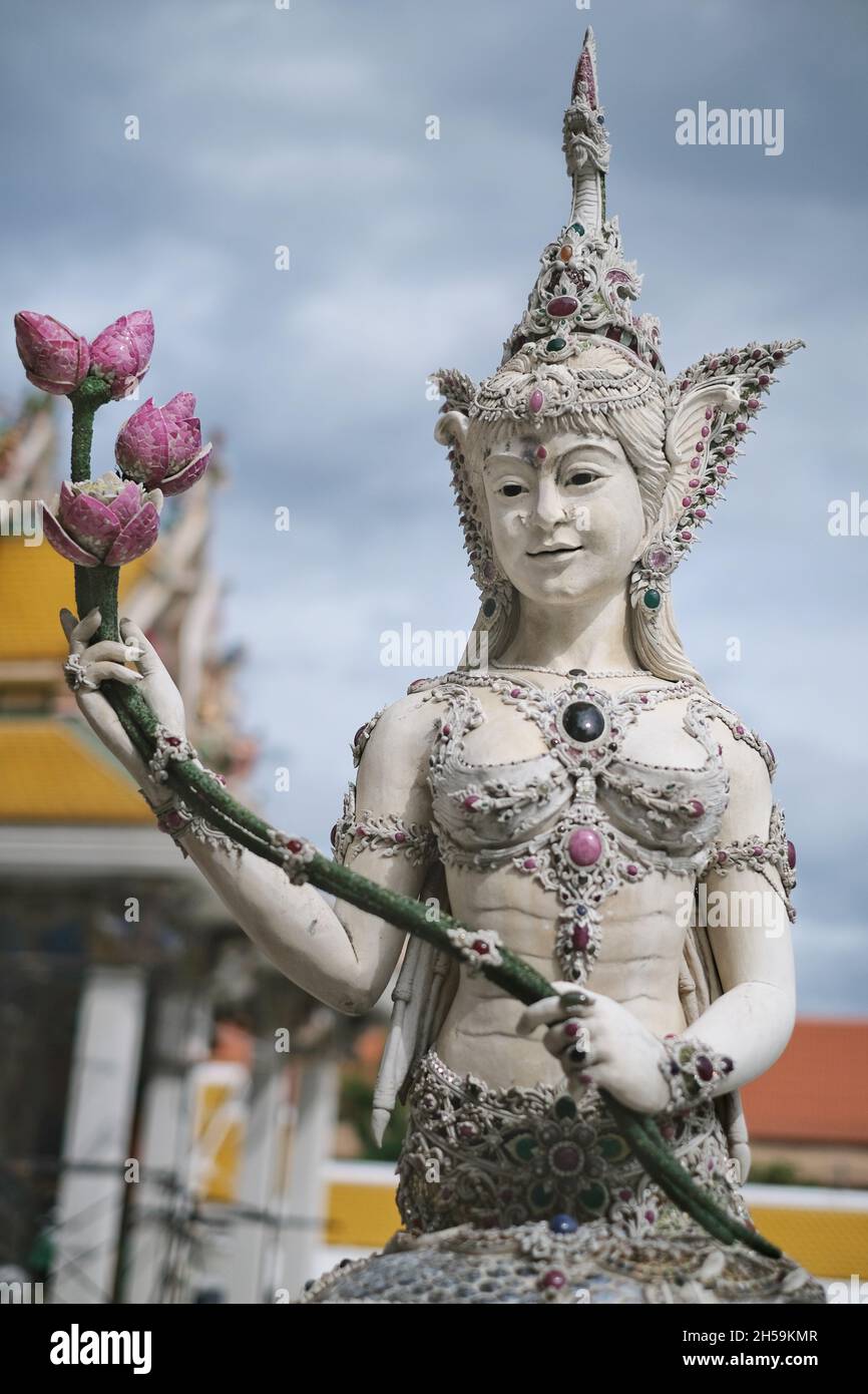 Bangkok / Thailand - 2021/11/01: A pearl white statue of a Thai mythical goddess holding a bunch of lotus flowers at  Wat Pariwat. A temple with Thai Stock Photo