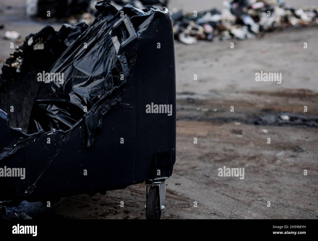 Melted trash bin in street. Unknown pests burned a plastic trash can. Stock Photo