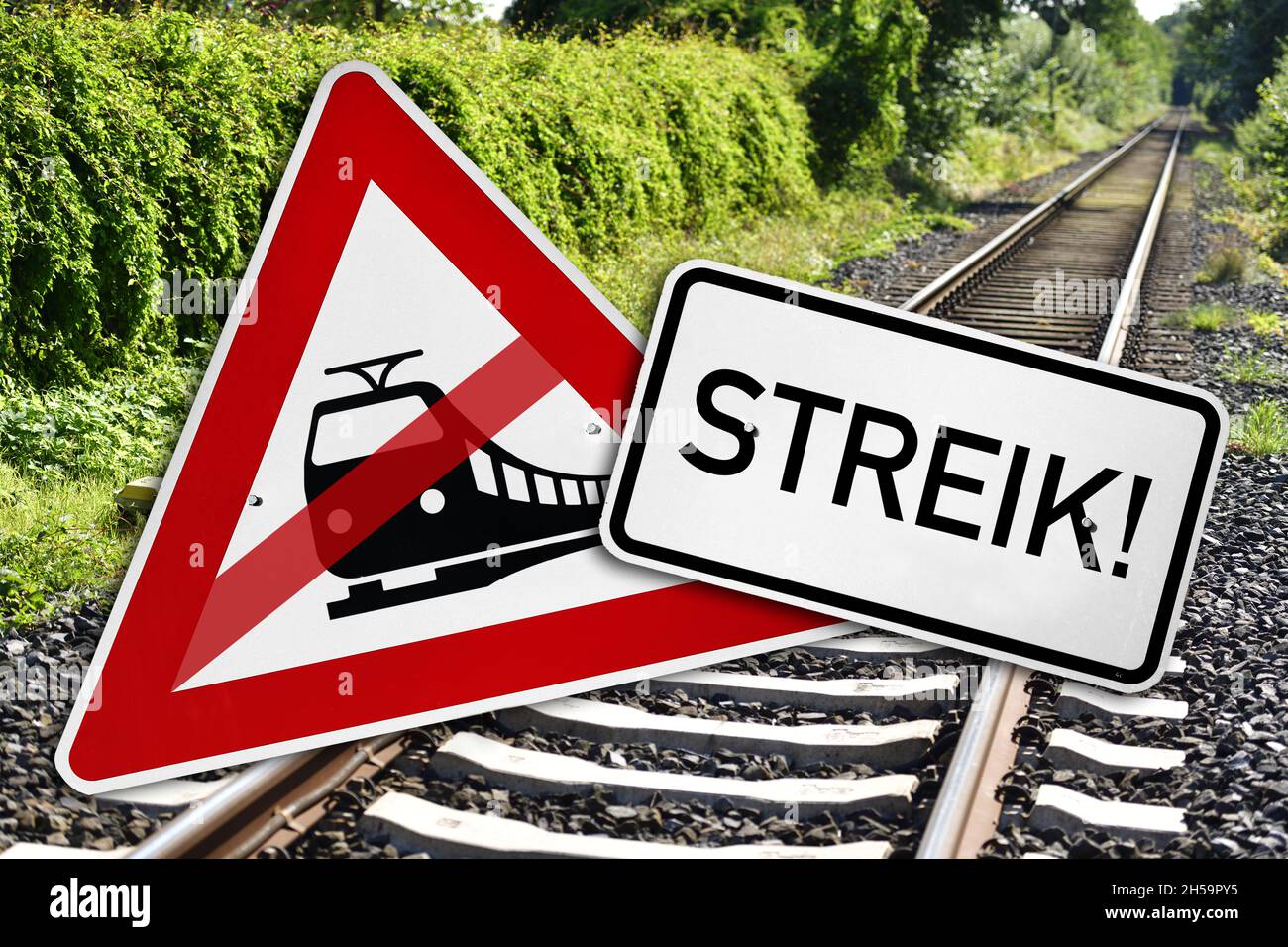 FOTOMONTAGE, Durchgestrichenes Verkehrsschild Bahnübergang und Schild mit Aufschrift Streik vor leeren Bahngleisen, Symbolfoto Bahnstreik Stock Photo