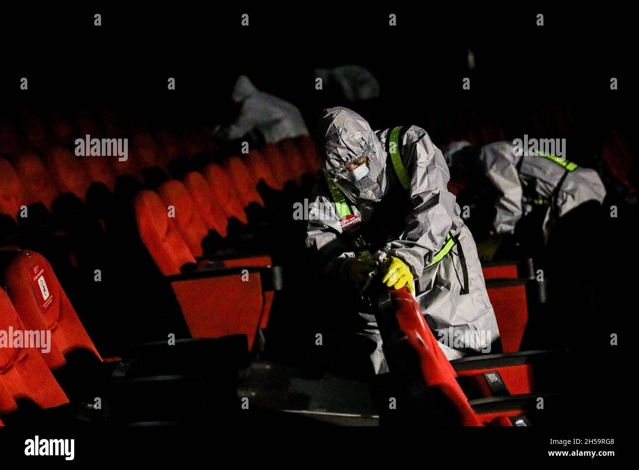 Workers wearing a protective kit sprays disinfectant to sanitize a movie theater as malls prepare to reopen at Robinsons Galleria mall in Quezon City, Metro Manila, Philippines. Stock Photo