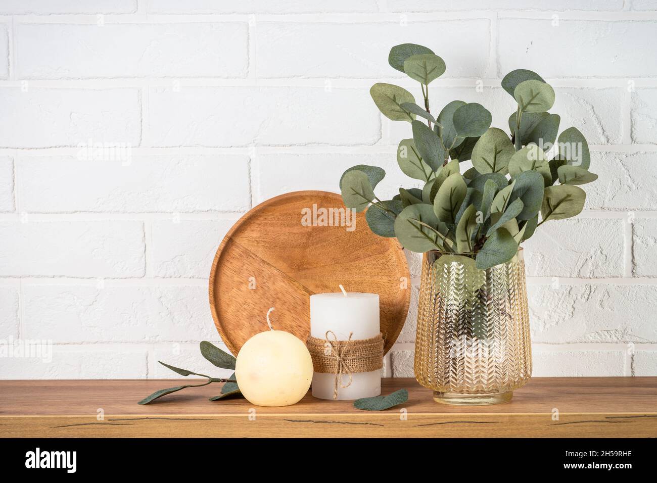Eucalyptus leaves in golden vase, candles, and golden decor at white