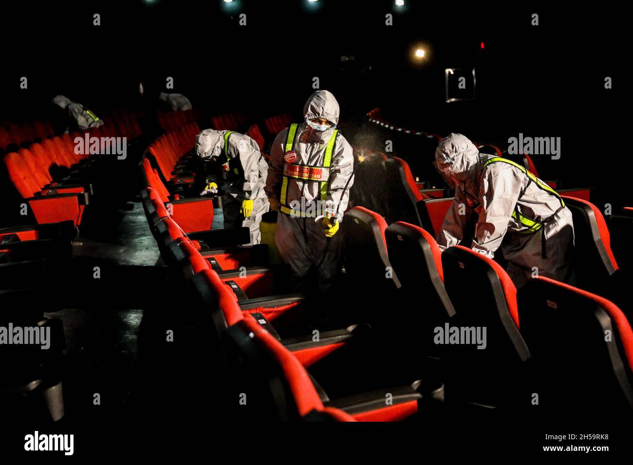 Workers wearing a protective kit sprays disinfectant to sanitize a movie theater as malls prepare to reopen at Robinsons Galleria mall in Quezon City, Metro Manila, Philippines. Stock Photo