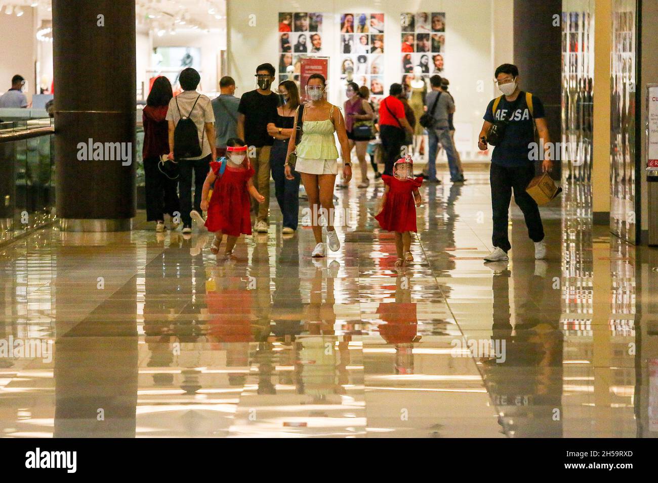 People wearing protective masks and face shields walk inside a shopping