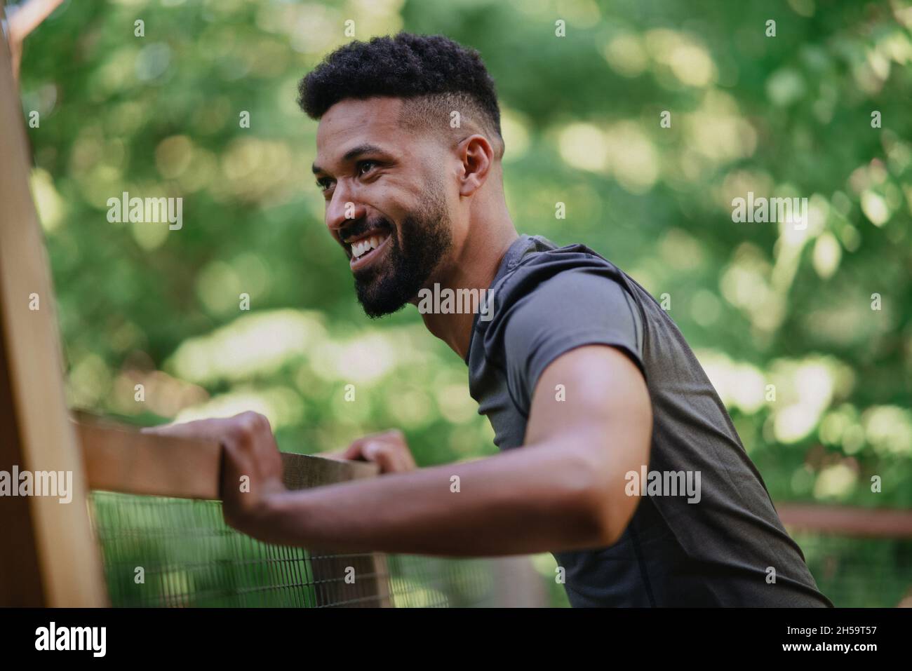 Happy young man doing exercise outdoors on terrace of tree house, weekend away and digital detox Stock Photo