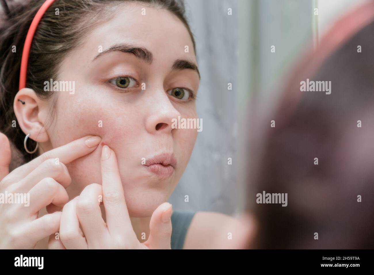 Young beautiful teenage girl touching her face before the mirror. Close ...
