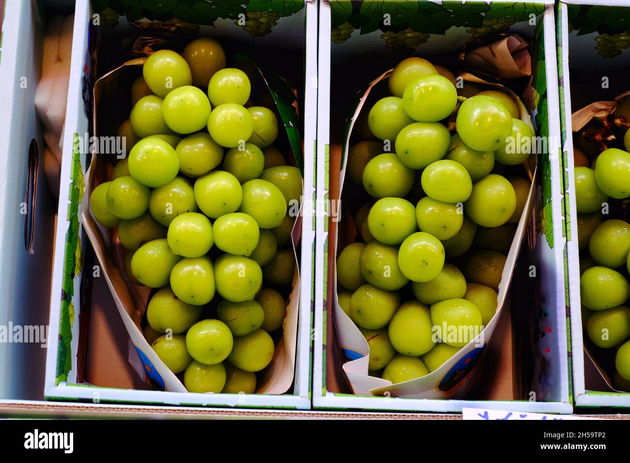 A bunch of ripe green grapes, nicely packaged in a box at a fresh market. Stock Photo