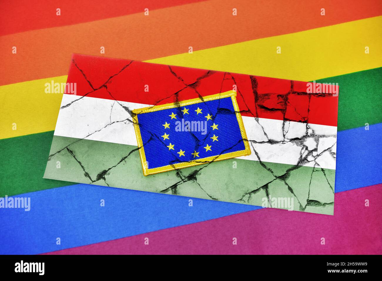FOTOMONTAGE, Fahnen von EU und Ungarn auf gebrochenem Grund und Regenbogenfahne, Streit um ungarisches LGBTQ-Gesetz Stock Photo