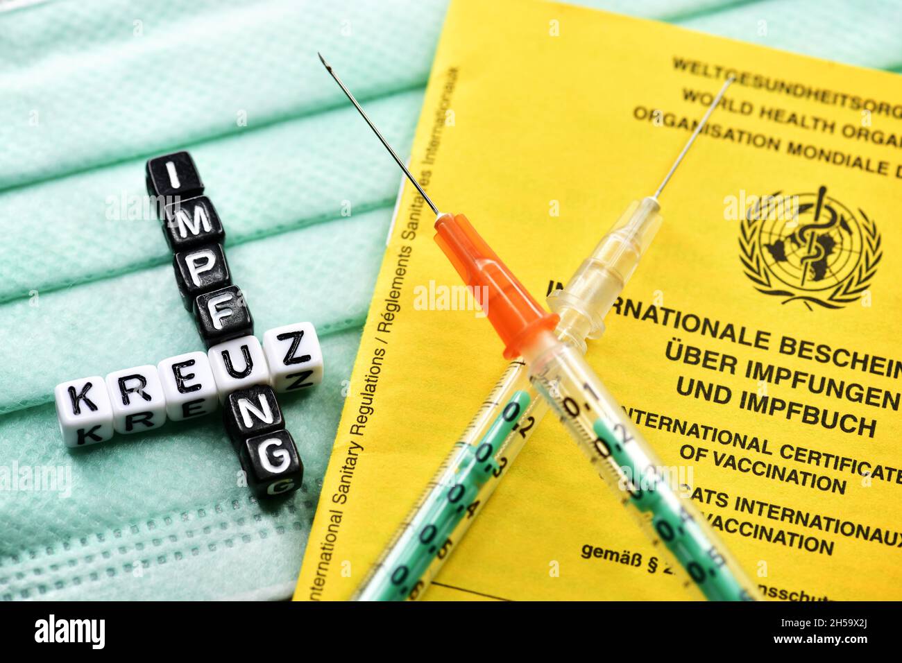 Zwei gekreuzte Spritzen mit Impfpass und Schriftzug Kreuzimpfung Stock Photo