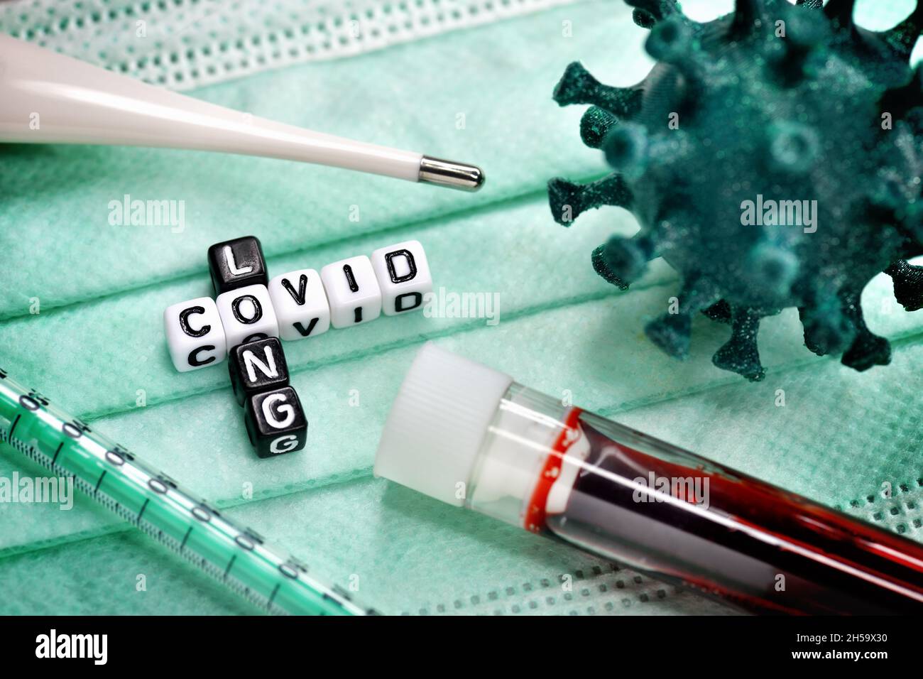 Buchstabenwürfel bilden den Schriftzug Long Covid neben Blutprobe und Coronavirus-Modell Stock Photo