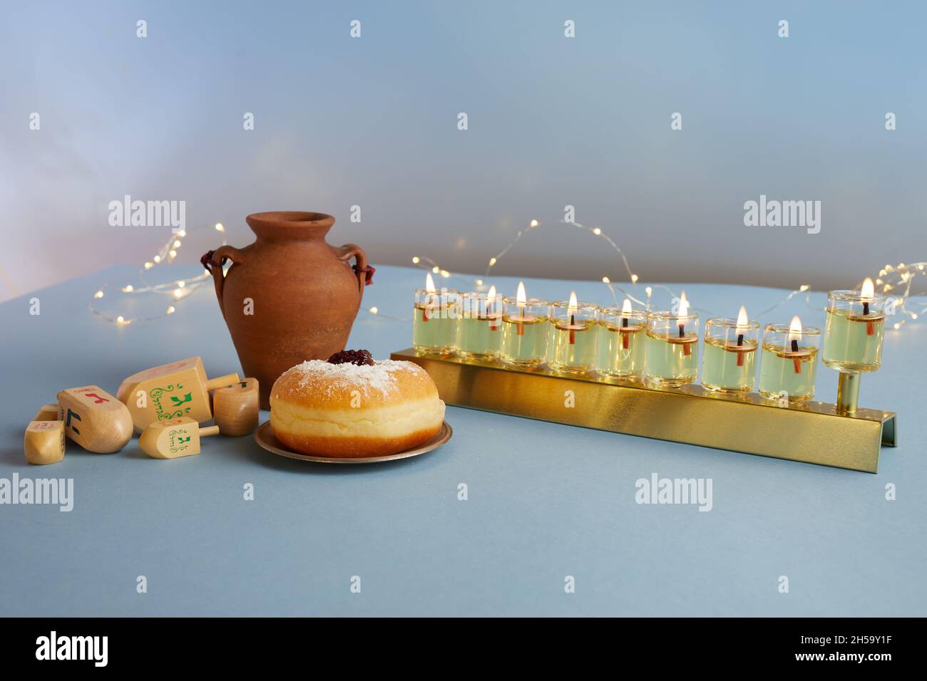 Jewish holiday Hanukkah background with menorah- traditional candelabra, spinning top and doughnut on blue background Stock Photo