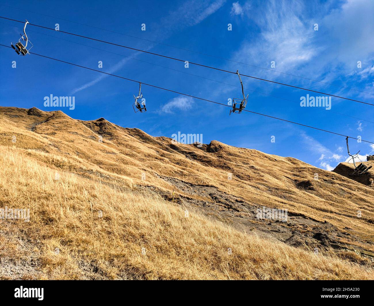 chairlift in autumn. elm ski resort in switzerland. Ski chair lift. Lush autumn meadows with blue sky Stock Photo