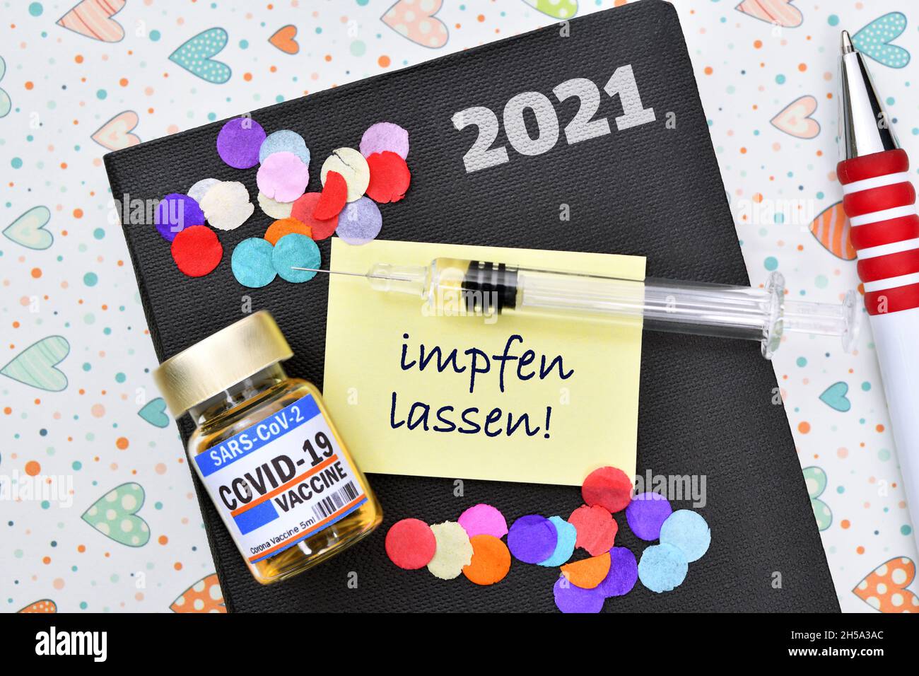 FOTOMONTAGE, Kalender mit Zettel, Spritze, Impfstoff und Aufschrift impfen lassen Stock Photo