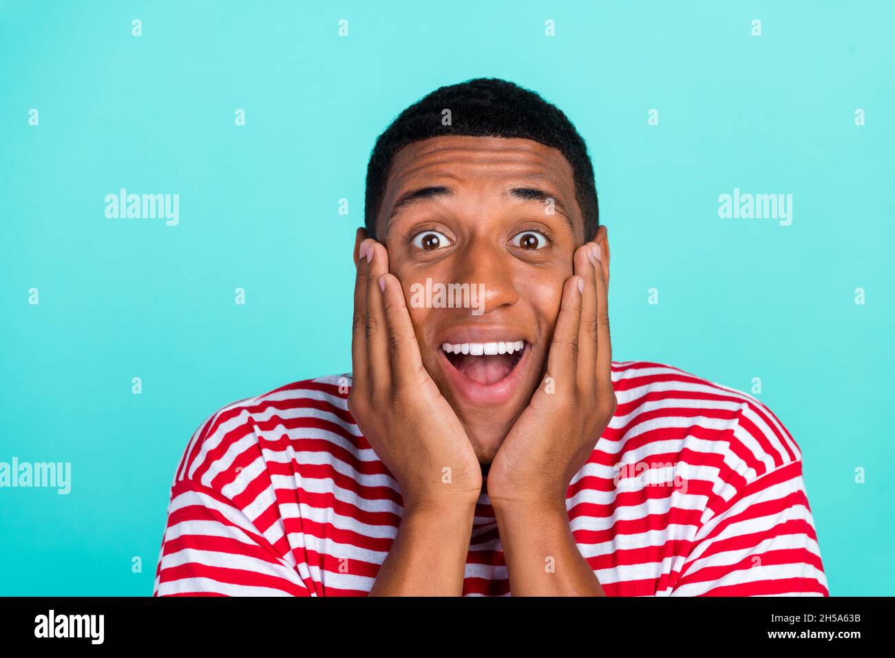 Photo of funny impressed young guy dressed red t-shirt smiling arms cheeks isolated turquoise color background. Stock Photo
