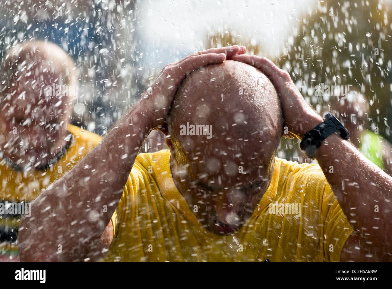 Man covering his bald head with his hands under the rain looking as arrested person Stock Photo