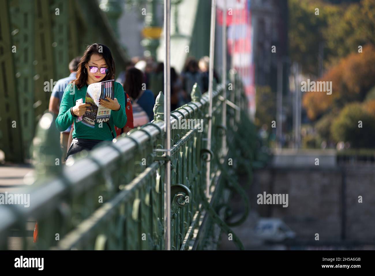 Woman crossing Liberty bridge in Budapest while reading a tourist guide Stock Photo