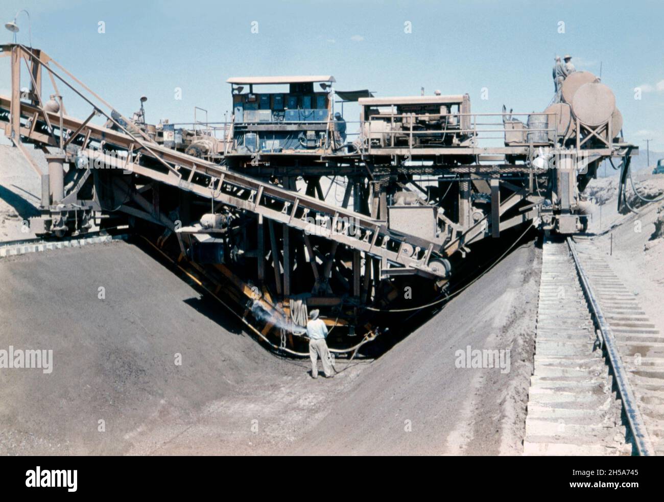 Construction work on the Wellton-Mohawk canal, near Yuma, Arizona, USA in the early 1950s. Here the workers are using the canal ‘trimmer’, a giant mechanical device on rails that digs out spoil and creates the canal’s profile. The Wellton-Mohawk Irrigation and Drainage District is located in south-west Arizona, east of Yuma, built between 1949 and 1957. It allows the irrigation in the Lower Gila valley with water from the Colorado river via the Gila Canal to the Wellton-Mohawk Canal, where it is pumped around 160 feet to the headwaters – a vintage 1950s photograph. Stock Photo